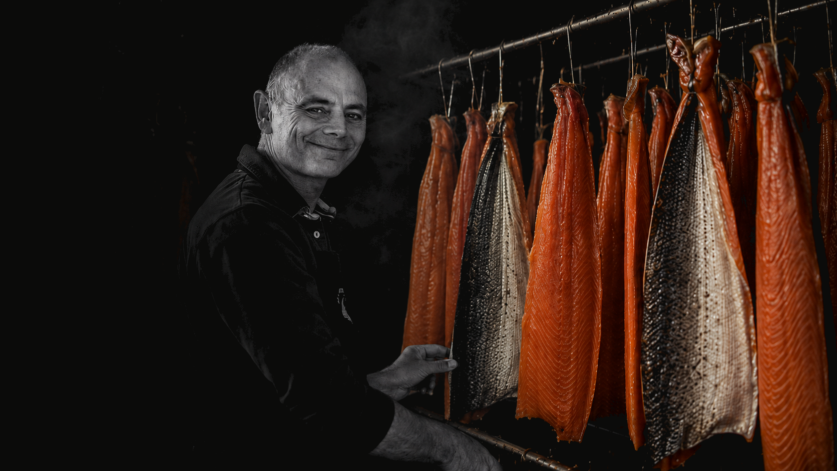 Rodolphe Belghazi devant les poissons fumés suspendus dans l'atelier Le Saumonier