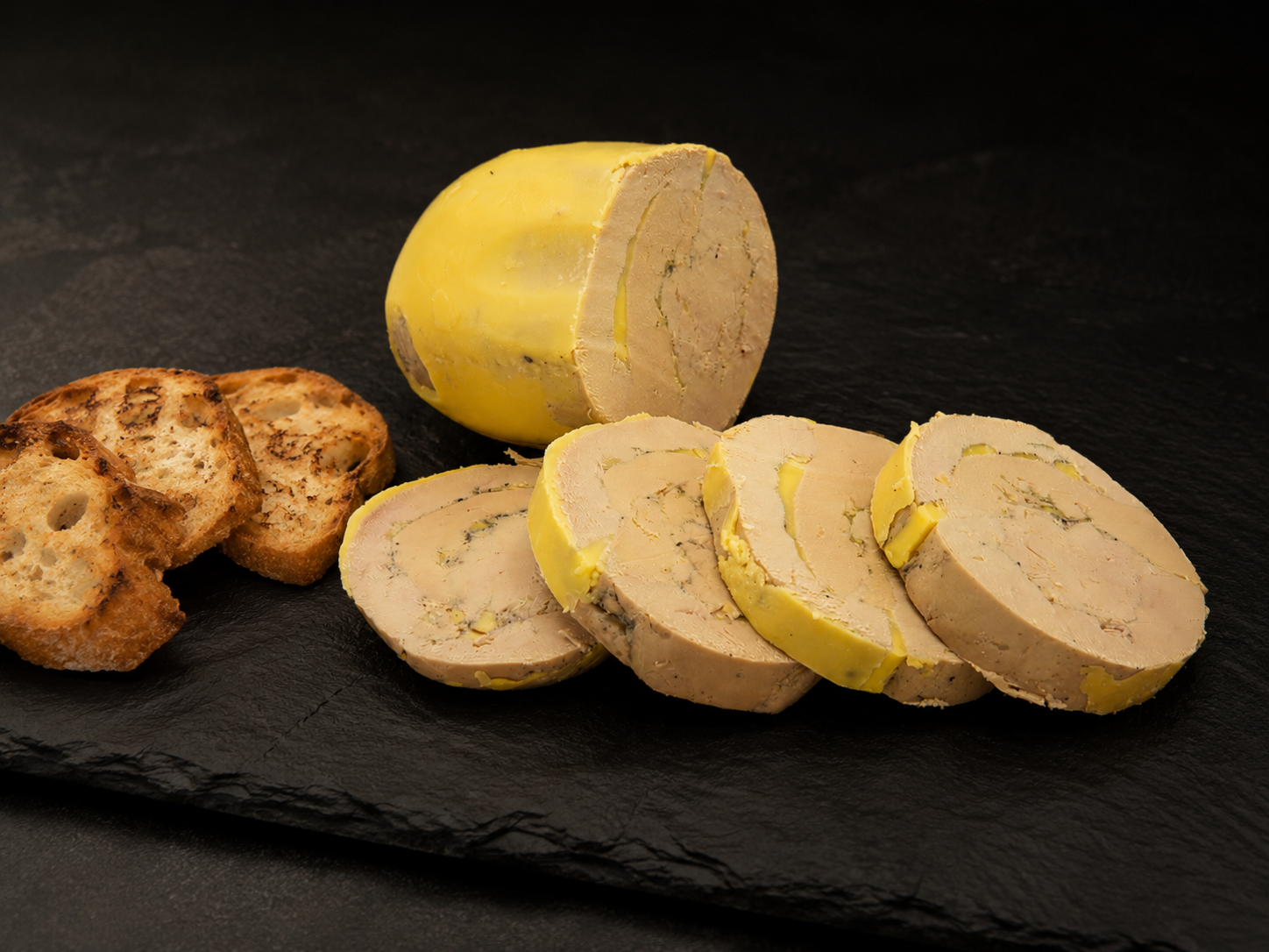 Foie gras maison entier et coupé en tranches, avec des toasts