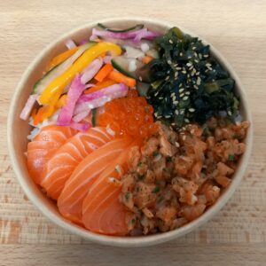 chirashi avec tartare de saumon, sashimi de saumon, wakamé, légumes marinés en julienne, oeufs de saumon au centre