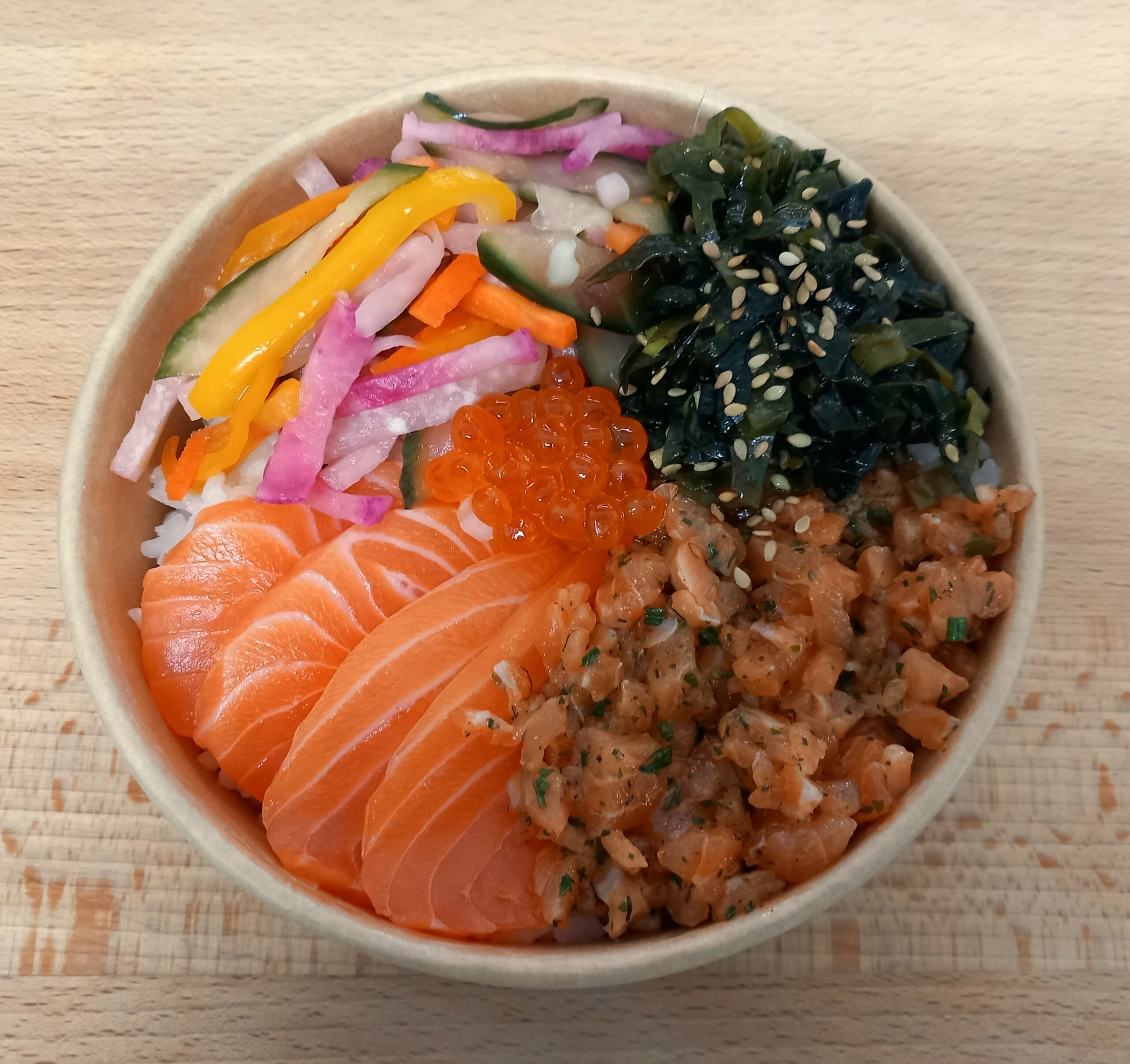 chirashi avec tartare de saumon, sashimi de saumon, wakamé, légumes marinés en julienne, oeufs de saumon au centre
